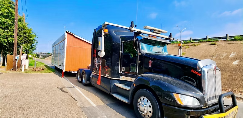 Black truck transporting a large orange container.